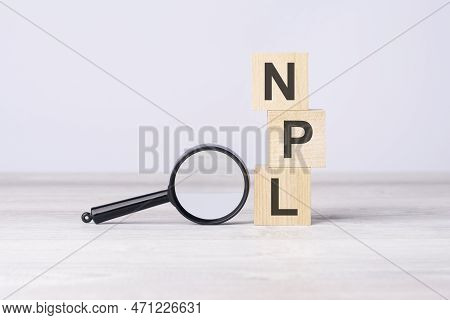 Concept Non Performing Loans Or Npl. Text On Wooden Cubes Under A Magnifying Glass.