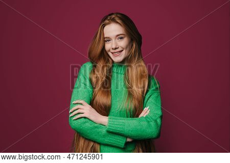 Cheerful Young Woman With Ginger Long Hair Smiling Happily While Looking At Camera Dressed In Green 