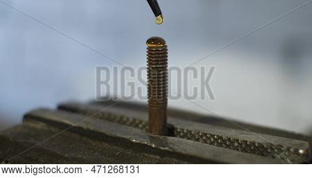 A Drop Of Golden Oil Falls On An Old Rusty Bolt. The Oil Lubricates The Surface Of The Old Bolt Prov