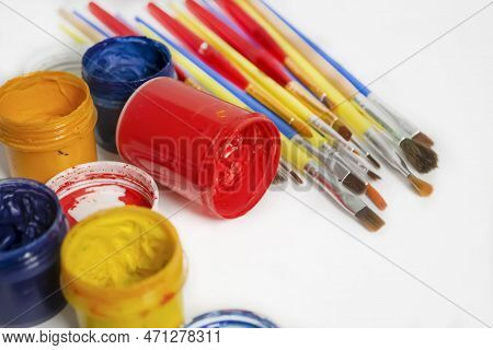 Jars Of Colored Paint Stand Next To The Brushes. For Artists, There Are A Lot Of Paints And Brushes.