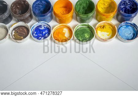 Jars Of Watercolor Paint Stand In A Row. A Number Of Watercolors. Color Watercolor With Open Lids On