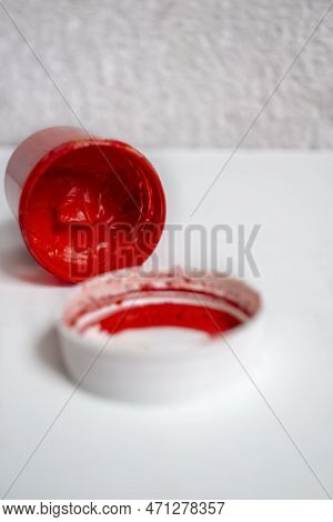 On The White Table Of The Jar Are Watercolors In Red. An Inverted Can Of Red Watercolor. A Jar Of Re