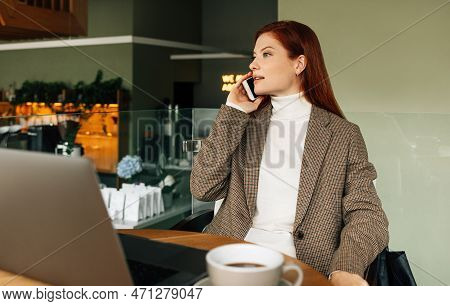 Businesswoman In Formal Wear Talking On Mobile Phone While Sitting In Cafe