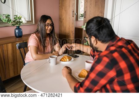 Young Diverse Loving Couple Eating Croissant And Talks Together At Home In Breakfast Time. Communica