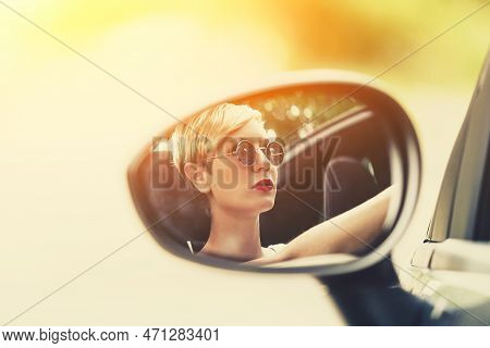 Young Blonde Attractive Woman Smiling And Looking Straight While Driving A Car.