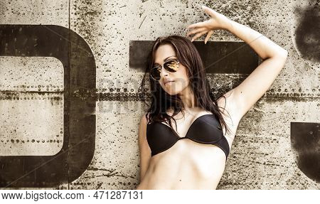 Portrait Of A Young Girl With Mimetic Military Dress Near The Old Abandoned Broken Plane. Concept Mi