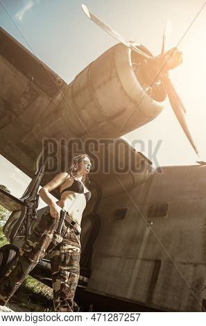 Portrait Of A Young Girl With Mimetic Military Dress Near The Old Abandoned Broken Plane. Concept Mi