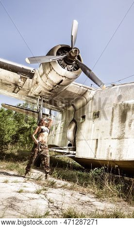 Portrait Of A Young Girl With Mimetic Military Dress Near The Old Abandoned Broken Plane. Concept Mi