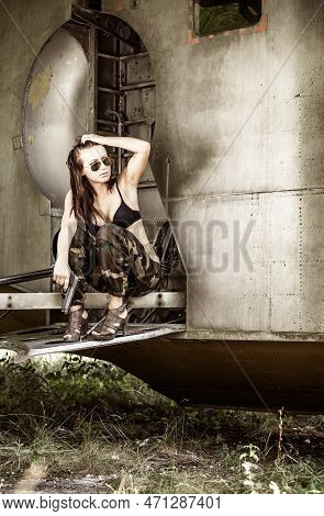 Portrait Of A Young Girl With Mimetic Military Dress Near The Old Abandoned Broken Plane. Concept Mi