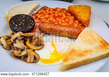 White Board With Full English Breakfast With Bacon, Fried Egg, Beans, Tomato, Roasted Sausage, Black
