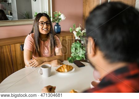 Young Diverse Loving Couple Eating Croissant And Talks Together At Home In Breakfast Time. Communica