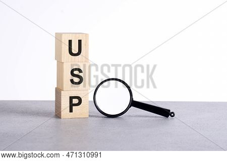 Usp - Unique Selling Proposition - Text Wooden Cube Blocks And Magnifying Glass On Grey Table