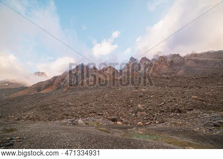 Scenic Alpine Landscape With Rocky Mountains In Dense Low Clouds In Morning Sunlight. Colorful Mount