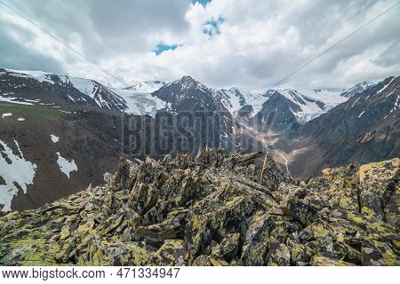 Vivid Landscape Near Precipice Edge With Sharp Rocks With View To Large Snowy Mountains And Glacier 