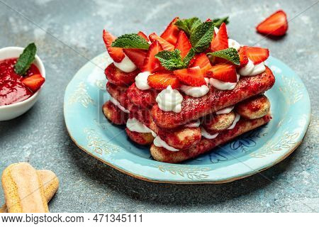 Italian Dessert Tiramisu Cake With Fresh Strawberry, Biscuit And Whipped Cream And Mint On A Dark Ba