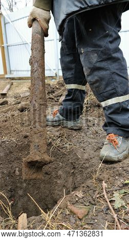 A Village Worker Pulls Out A Heavy Rusty Rounded Iron Post From The Excavated Soil, Excavation With 