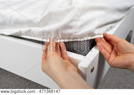 A White Satin Sheet With An Elastic Band Is Put On The Mattress Of The Bed, A Close-up Of The Hands.
