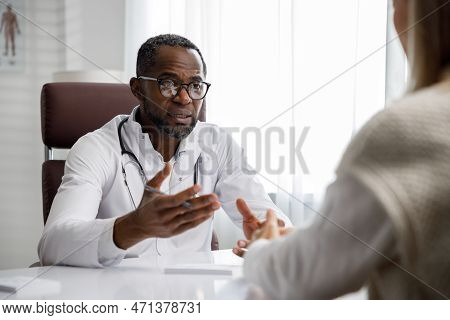 African American Doctor, Receives A Patient, Listens To Complaints, Makes Diagnostics. Writes Data. 