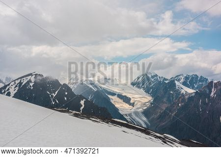 Dramatic Landscape With Long Glacier Tongue And High Snow Mountains In Cloudy Sky. Wonderful Aerial 