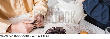 Cropped View Of Muslim Woman Pouring Milk Near Husband During Suhur In Morning, Banner.