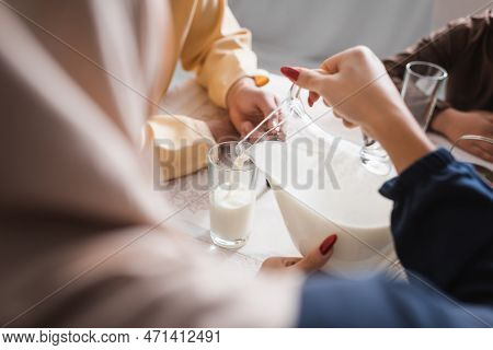 Arabian Woman Pouring Milk During Suhur With Family In Morning At Home.