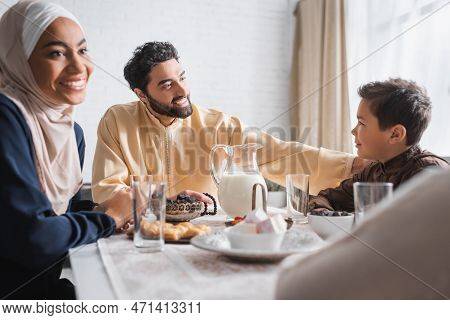 Muslim Father Looking At Son Near Family During Suhur In Morning At Home.