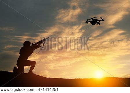 Soldier Trying To Shoot Down Reconnaissance Drone Against The Backdrop Of A Sunset. Soldier Shoots A
