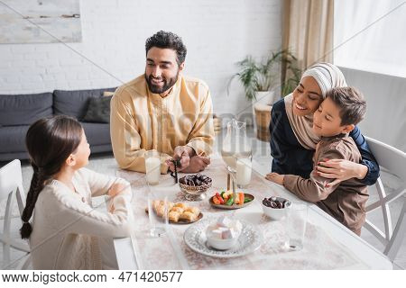 Positive Muslim Family Sitting Near Food During Suhur In Morning At Home.