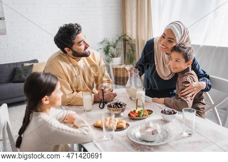 Smiling African American Woman In Hijab Hugging Son Near Family During Suhur Breakfast In Morning.