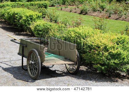 Viejo barril de madera rueda con rastrillo de jardín