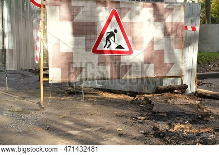 Construction Road Triangle Sign On Metal Fence Background. Preparation For Laying New Asphalt Paveme