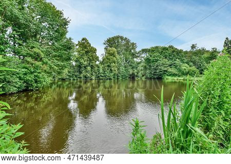 Amsterdam, Netherlands - 10 April, 2021: A River With Trees And Bushes In The Fore, Taken From A Mov
