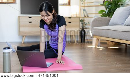 Woman looking at yoga teacher on laptop and doing light exercise in the living room at home, Watch l