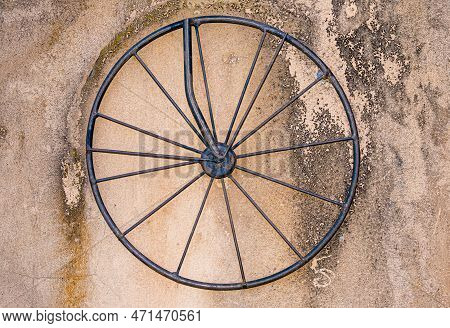Old Rod Iron Bicycle Wheel With Spokes On Dirty Concrete Stained Wall