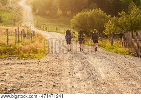 Group Of Female Hikers In Sunset Backlight On Gravel Dusty Road Heading To Pietrosul Rodnei Mountain