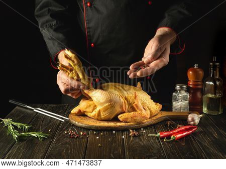The Chef Prepares Raw Rooster In The Kitchen. The Cook Adds Pepper To The Cock Before Frying. Prepar