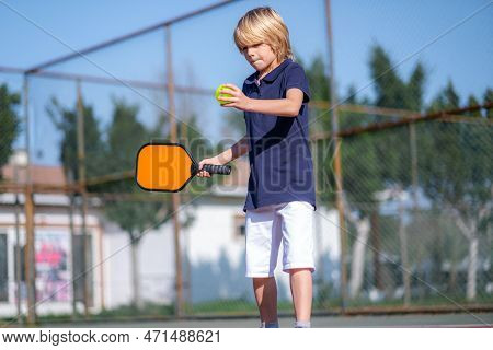 Happy Blonde Boy Playing Pickleball Game, Hitting Pickleball Yellow Ball With Paddle, Outdoor Sport 