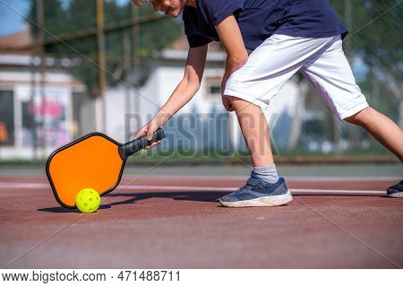 Happy Blonde Boy Playing Pickleball Game, Hitting Pickleball Yellow Ball With Paddle, Outdoor Sport 