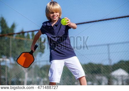 Happy Blonde Boy Playing Pickleball Game, Hitting Pickleball Yellow Ball With Paddle, Outdoor Sport 