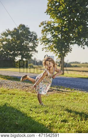 Charming Child In A Sundress Running Down The Street In The Suburbs