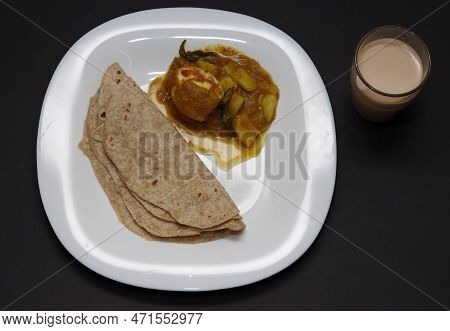 Indian Breakfast Chappathi, Egg Roast And Tea In Black Background