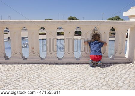 Child Boy Leaning On The Balustrade Of The Promenade Of Figueira Da Foz, Portugal. Beach Resort Of S