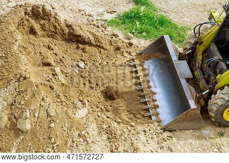 A Mini Tractor-loader Moves And Unloads Earth On A Construction Site. Mini Loader Bucket.