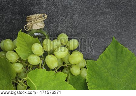 Grape Seed Oil.grape Vinegar. Oil In A Transparent Bottle And Green Grapes With Leaves On A Gray Sla
