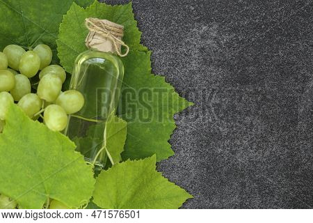 Grape Seed Oil.grape Vinegar. Oil In A Transparent Bottle And Green Grapes With Leaves On A Gray Sla
