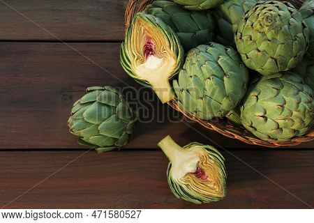 Wicker Basket With Fresh Raw Artichokes On Wooden Table, Flat Lay