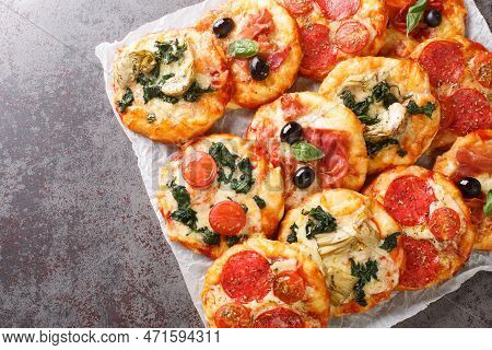 Italian Pizzette Mini Pizza Bites With Assorted Toppings Close-up On Parchment On The Table. Horizon