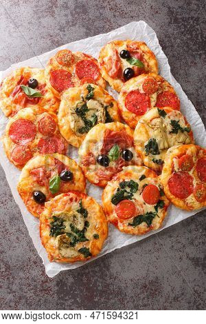 Homemade Mini Pizzas Pizzette With Meaty And Vegetarian Toppings Close-up On Parchment On The Table.