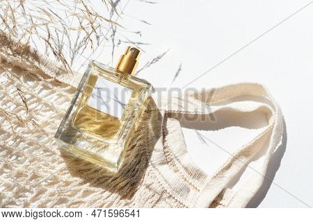 Transparent Bottle Of Perfume With Label And Cloth Shopping Bag, Wildf Grass On White Background. Fr