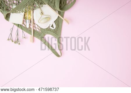 Cosmetic Products And Hygiene Items In A Green String Bag On A Pink Background. The Concept Of Susta